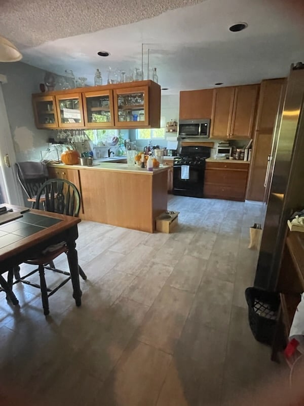 Modern kitchen with wood cabinetry, island counter, stainless steel appliances, and open floor plan dining area
